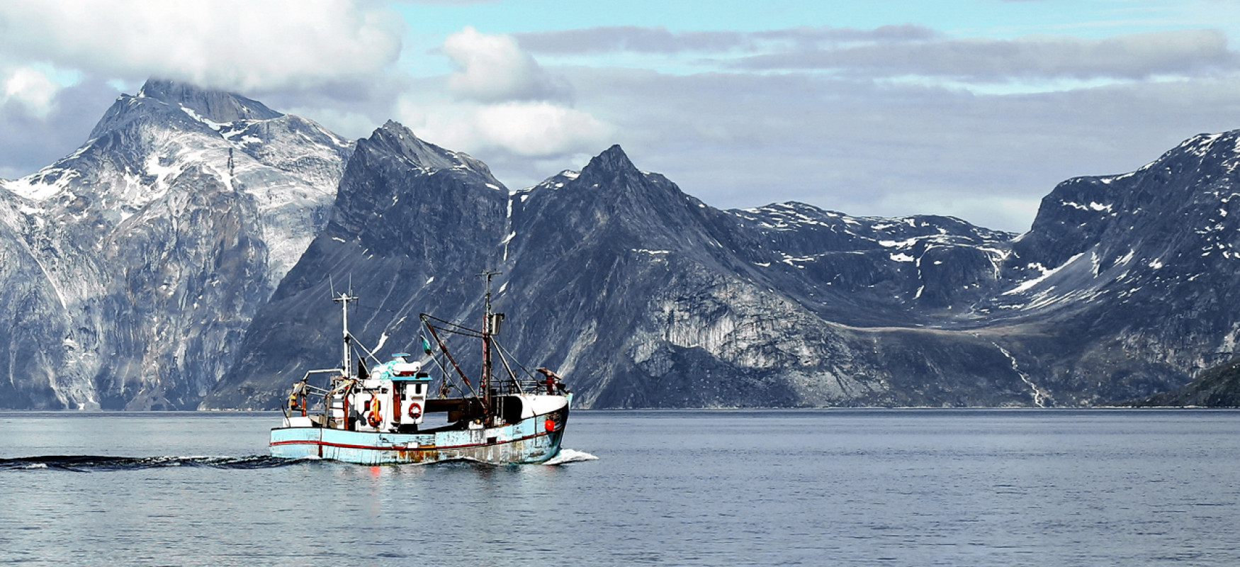 Fishing boat on calm water close to the coast of Greenland
