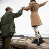 Man holding hands with girl walking by the sea with a prosthetic leg.