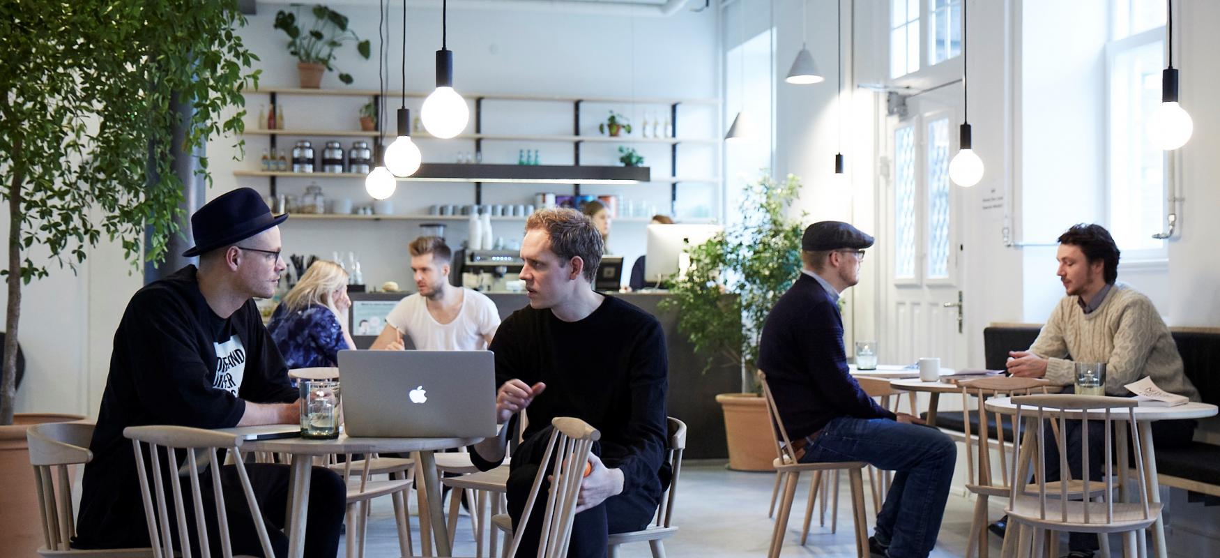people sitting at tables in a cafe and working