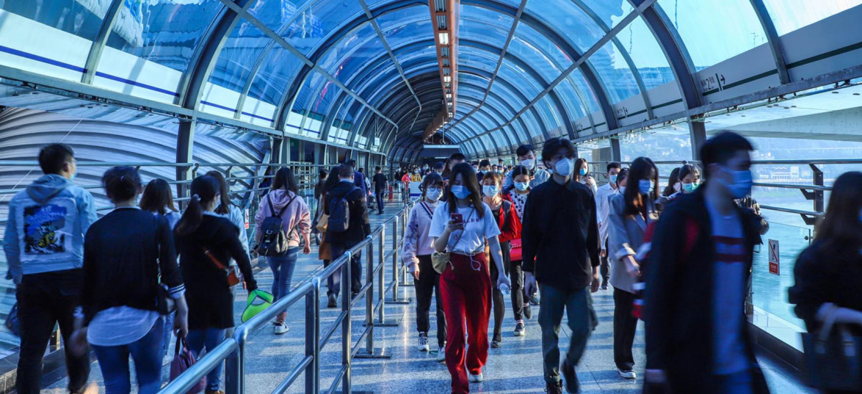 People in a train station glass walkway in Chongqing, China