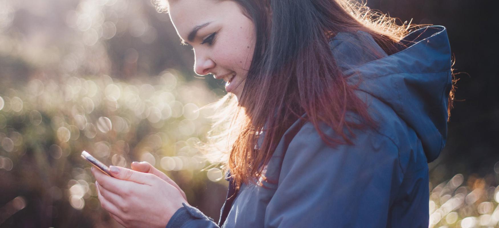 Healty woman using a smartphone in the woods. 